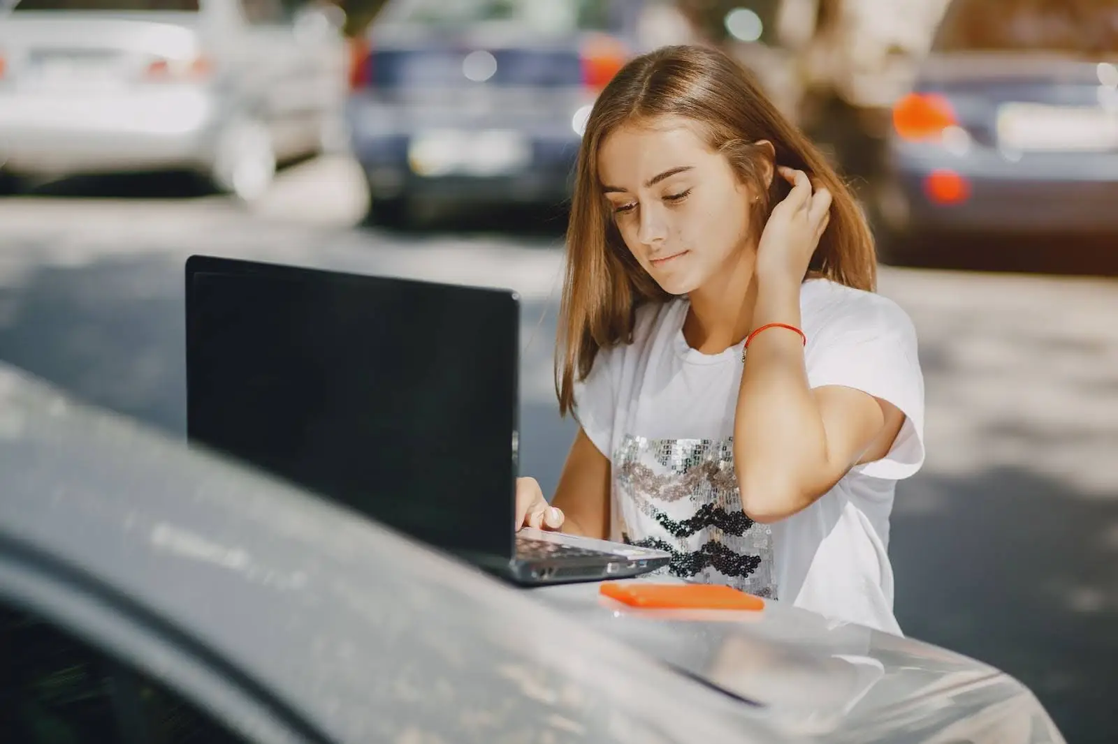 Girl sitting on a car trunk using a laptop with internet connection, representing why Comcast Internet Plans in San Diego are designed for modern households.