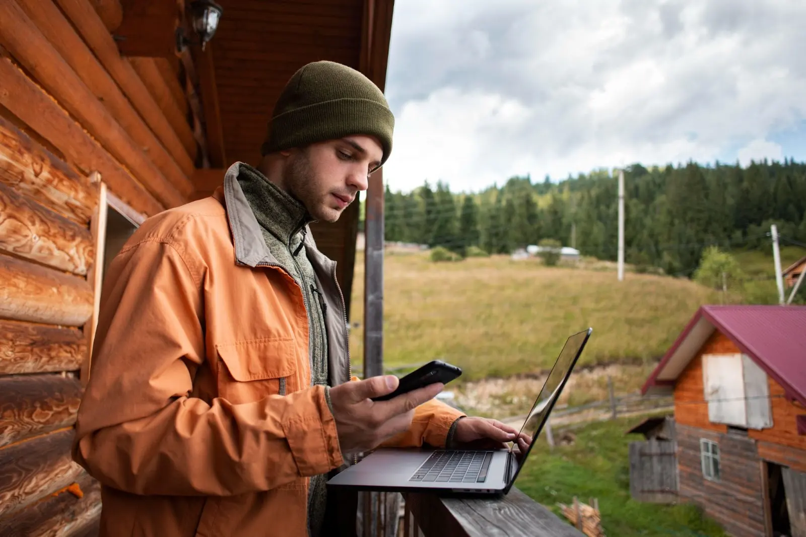 Man using a smartphone and laptop to access the internet, illustrating Windstream WiFi connectivity in rural areas.