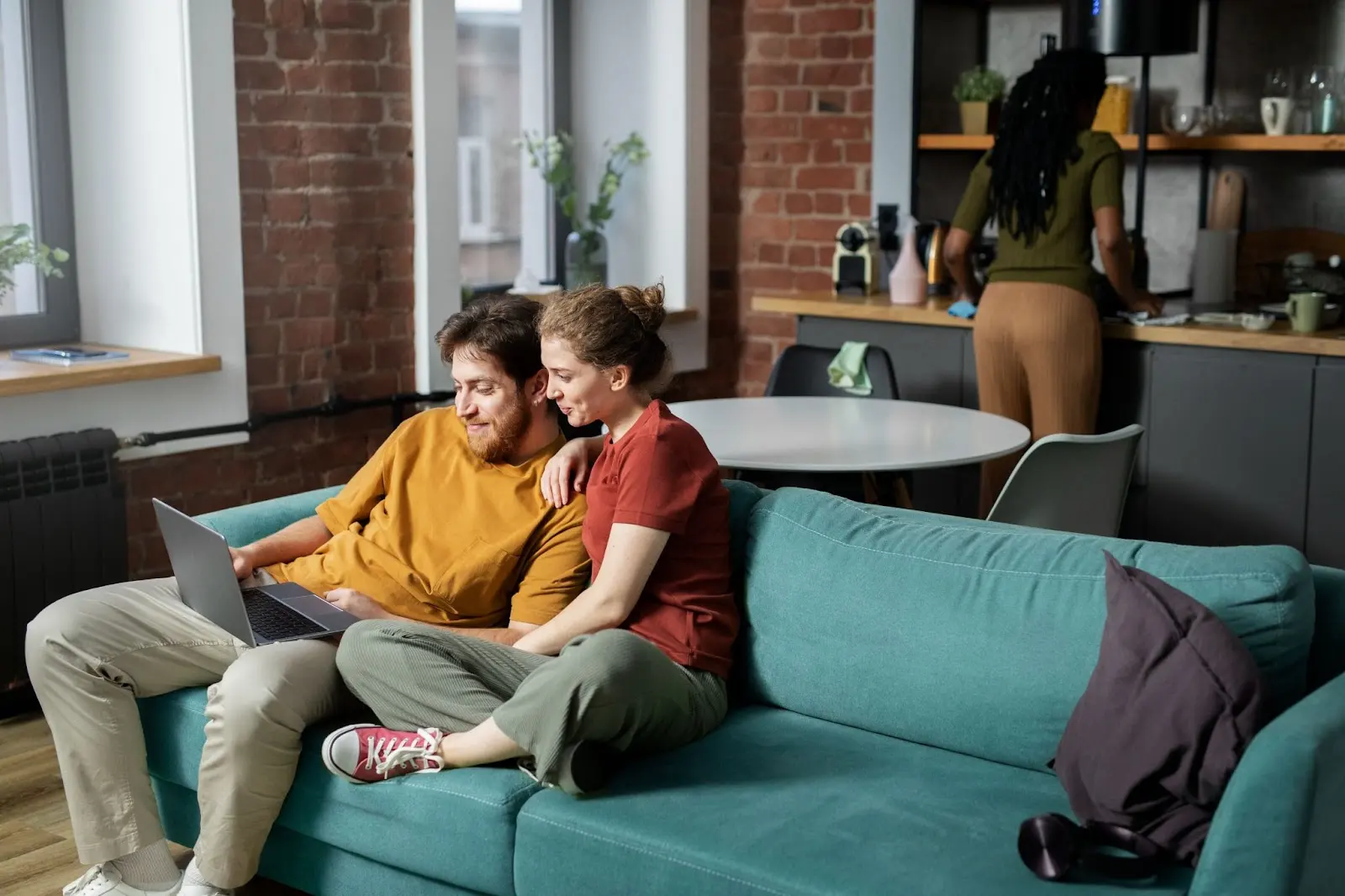 A smiling couple relaxing on a sofa while using a laptop together, enjoying internet service at home — illustrating the comfort and convenience of Windstream Bundles for families.