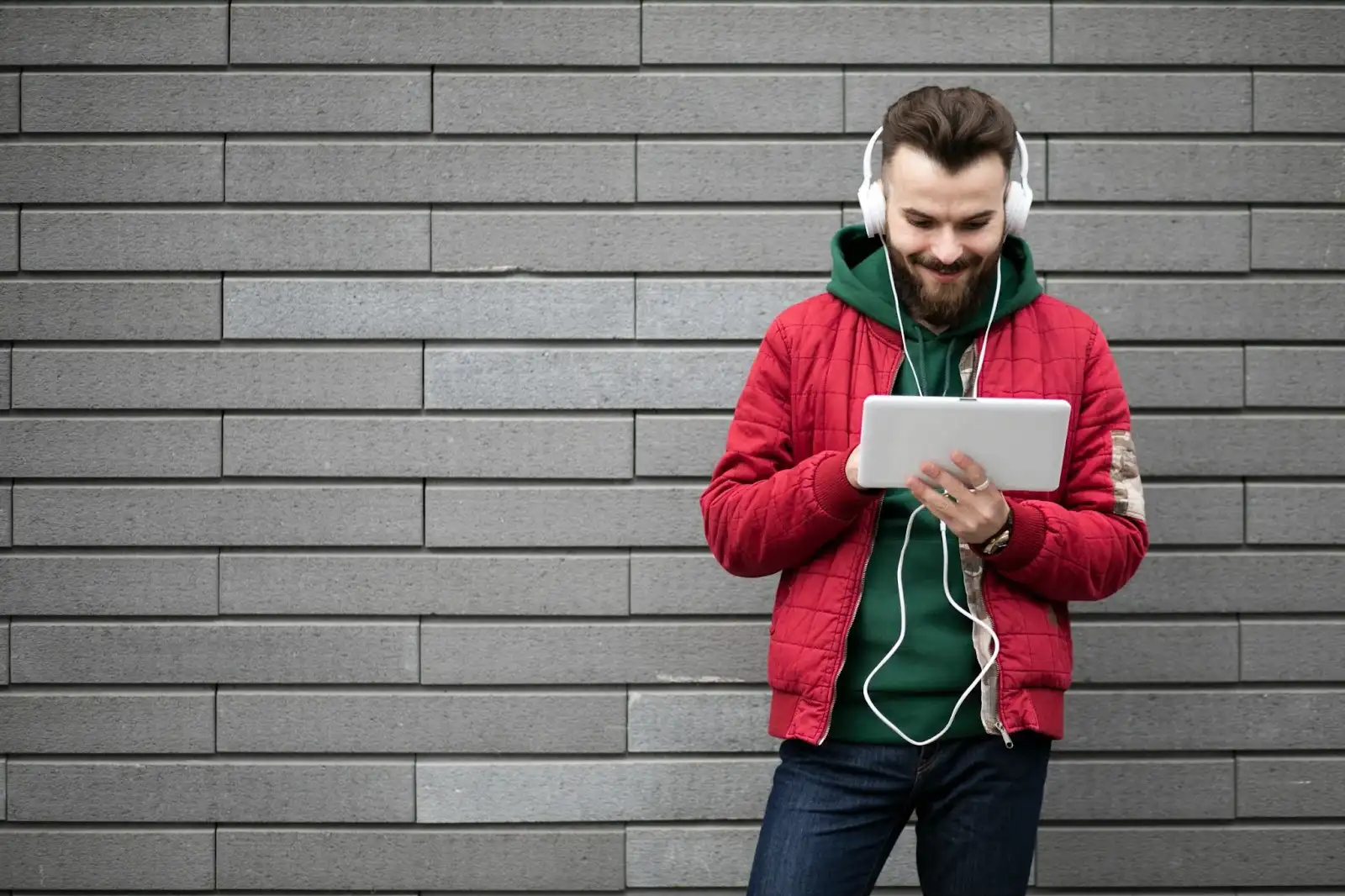 A young man wearing headphones sits comfortably while using a tablet, representing fast and reliable connectivity with Windstream Fiber in Paducah and its available plans and speeds.