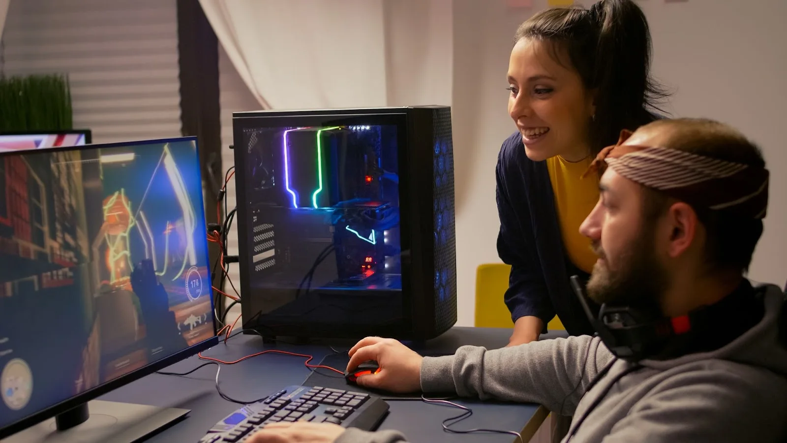 A young man intensely playing a game on his PC while a young woman beside him watches and enjoys the moment, illustrating the excitement of gaming powered by Windstream Internet Service.